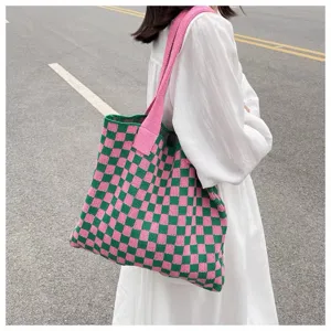Lifestyle shot of a woman carrying a pink and green checkered knitted tote bag on her shoulder