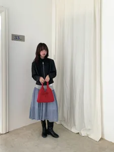 Stylish red knitted handbag with bow detail held by a model in a minimalist setting