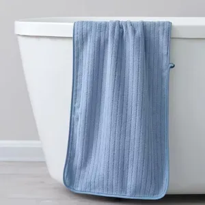 Toalla de vellón de coral azul gruesa con textura de canalé colgada en una bañera
