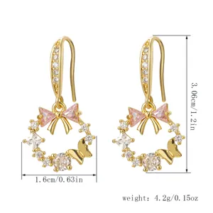 Detail of gold-plated earrings with pink zircons featuring bow and butterfly dimensions