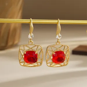 Detail view of vintage red crystal gold earrings with intricate hollow design