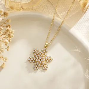 Close-up of golden snowflake pendant necklace with sparkling CZ stones on ceramic dish