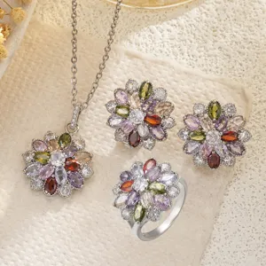 Close-up of rainbow zircon flower pendant, earrings, and ring on a textured background