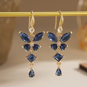 Gros plan détaillé de boucles d'oreilles papillon dorées avec pierres de zircon bleues