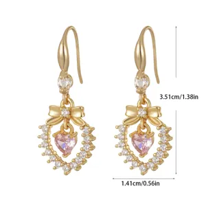 Macro view showing dimensions of gold-plated bow earrings with pink heart zircon