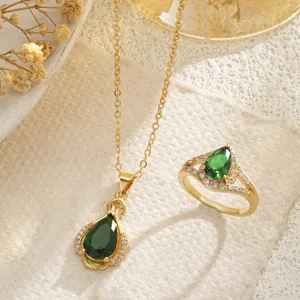 Macro detail of elegant emerald green pear-shaped gold necklace and ring jewelry set