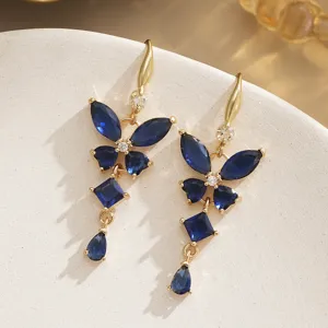 Vue détaillée des boucles d'oreilles papillon en saphir avec monture dorée et zircons