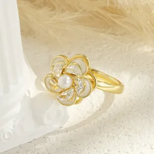 Detailed view of a gold-toned rotating flower ring featuring a pearl center and crystals