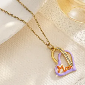 Macro view of gold-tone heart pendant featuring purple enamel and Mom script engraving