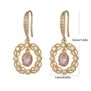 Close-up of gold-plated drop earrings with pink zircons and hollow lace details