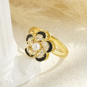 Detailed macro shot of a rotatable golden flower ring with black enamel and pearl center