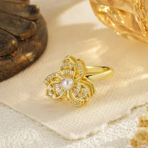 Close-up detail of a gold rotatable flower ring with a center pearl and zircon stones.
