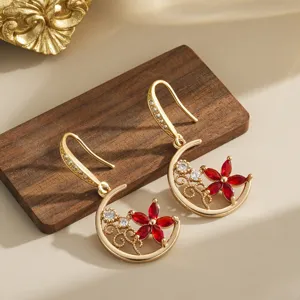 Detailed macro view of vintage earrings featuring red crystal flowers and gold moon pendants