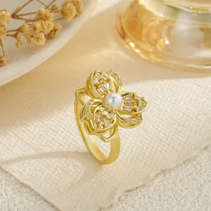 Close-up of elegant gold rotating flower ring with pearl center and crystals.