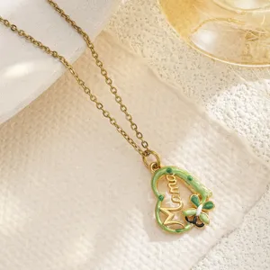 Close-up of heart pendant with Mama lettering and green enamel bee detail.