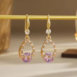Close-up of gold-plated hollow teardrop earrings featuring pink zircon crystal stones