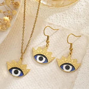 Retro gold-plated Evil Eye necklace and earrings set with blue enamel details on textured paper