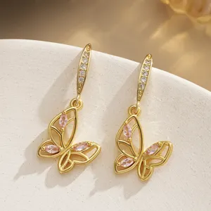 Close-up of gold-plated butterfly earrings with pink zircon inlay and hollow wings