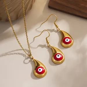 Close-up of gold-plated evil eye necklace and earrings set with red enamel detail