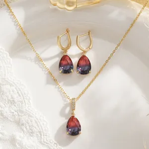 Close-up of vintage necklace and earrings set featuring red-purple gradient teardrop stones