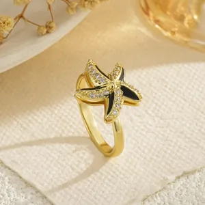Detailed macro view of a rotating gold starfish ring with black enamel and zirconia