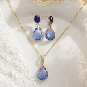 Primer plano de un elegante conjunto de joyas doradas con cristales azules en gota