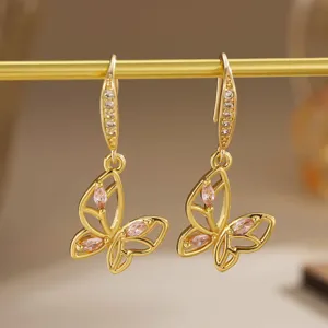 Detailed macro shot of gold-plated butterfly earrings featuring pink cubic zirconia