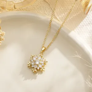 Detailed close-up of a gold rotatable snowflake pendant necklace with cubic zirconia