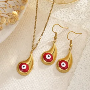 Detail shot of a gold-plated teardrop Evil Eye necklace and earring set on cream fabric.
