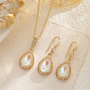 Close-up of elegant bridal jewelry set featuring iridescent teardrop crystal pendant and earrings.