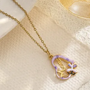 Close-up detail of a gold heart pendant necklace featuring Mama text and purple enamel