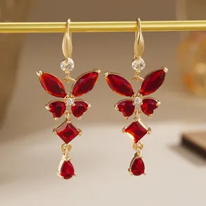 Detailed view of vintage gold butterfly earrings featuring faceted red zircon stones.