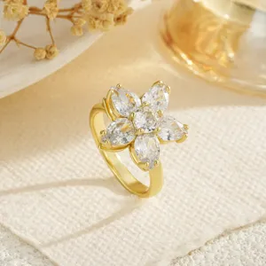 Macro view of an elegant gold flower ring with sparkling zircon petals on cream fabric