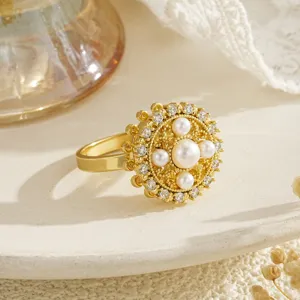 Close-up detail of a rotatable gold flower ring with pearls and clear cubic zirconia