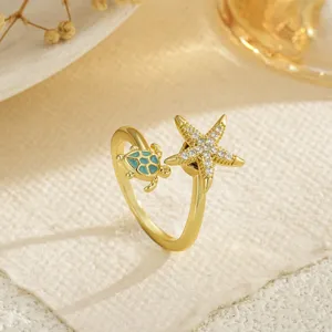 Close-up of golden adjustable ring with cz starfish and enamel turtle details.