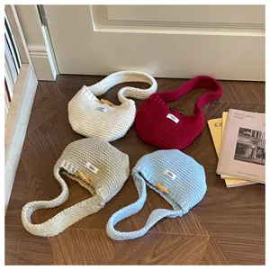 Four colorful handmade crochet mini handbags displayed on a warm wooden floor in cozy setting