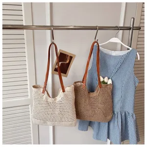 Two crochet hollow-out beach bags hanging on a rack with a blue checkered dress