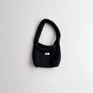 Detailed macro view of a black handmade style knitted handbag with white egg logo tag.