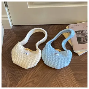 Close-up of cream and light blue knit handbags with wooden buttons and egg labels.
