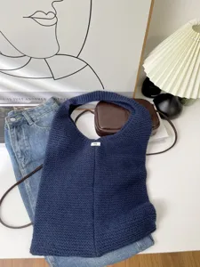 Detailed knit texture of a navy blue oversized tote bag in a cozy room setting