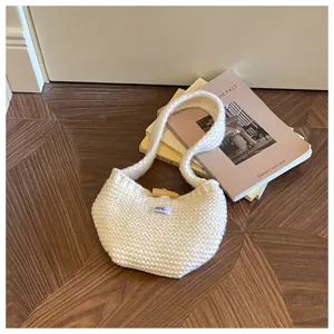 Close-up of a cream white knitted handbag featuring textured wool and wooden toggle