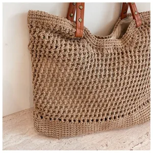Detail view showing the hollow woven texture of a beige cotton thread beach bag.