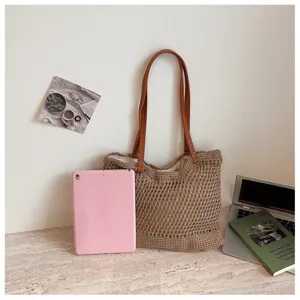 Handmade woven hollow straw beach bag shown with a pink tablet for size reference