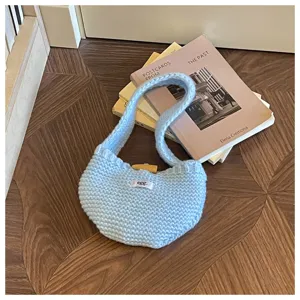 Close-up of a light blue knitted handbag with a wooden toggle and cozy aesthetic.