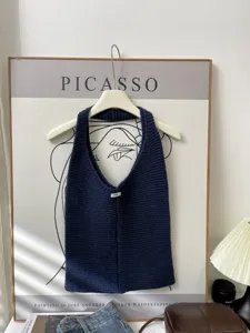 Close-up of a navy blue knitted tote bag on a hanger against an artistic Picasso background
