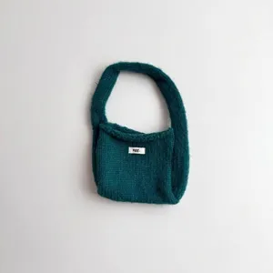 Detail showing the soft knit texture and logo tag of the teal handbag