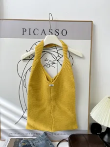 Detailed view of a yellow knitted tote bag hanging in a cozy home setting.