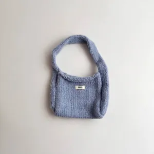 Detailed macro view of a light blue knitted mini handbag with white 'egg.' label on front