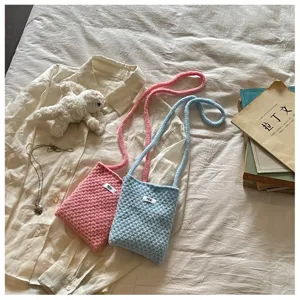 Detail of pink and blue knitted crossbody phone bags in a cozy lifestyle setting