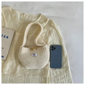 Detailed view of cream knitted mini bag with toggle closure next to a phone for scale